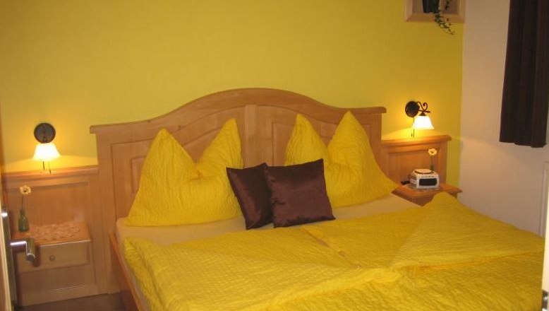 Guest room, © Fam. Schwalm Cozy guest room with yellow bedding and wooden furniture.