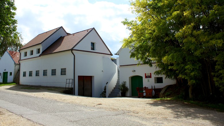 Ribisch Winery, © Weingut Ribisch White building with a red roof and green doors, surrounded by trees.