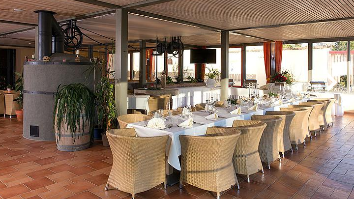Restaurant, © JUFA Elegant restaurant with laid table and wicker chairs.