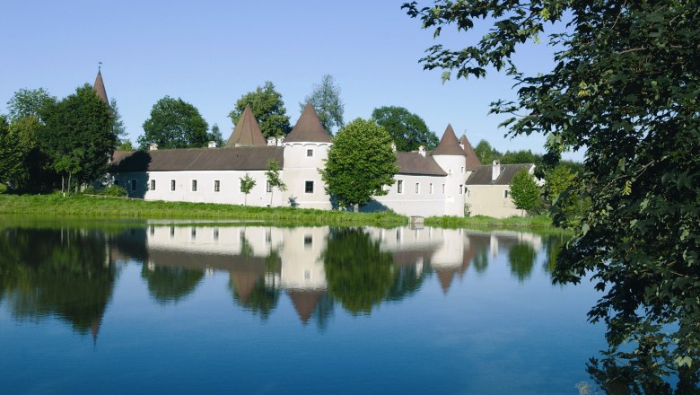 Market town of Pölla, © Marktgemeinde Pölla The castle with its pointed towers is reflected in a calm lake surrounded by trees.