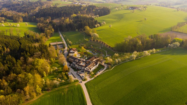 RelaxResort Kothmühle, © Florian-Schaumberger Aerial view of a resort surrounded by green fields and forests.