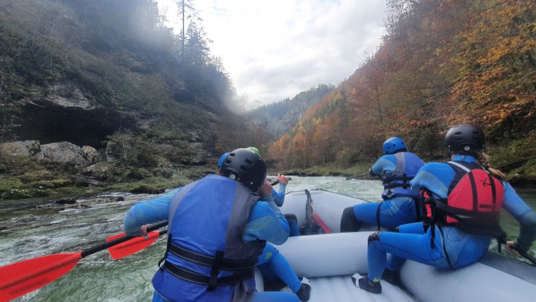 Rafting Wilderness Center Nasswald, © Georg Bergthaler Group rafting on a river surrounded by autumnal trees.