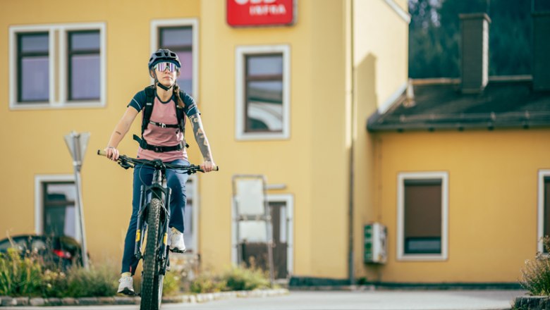 Aspang train station, © Wiener Alpen, Kremsl Person on bicycle in front of yellow building with ÖBB logo.