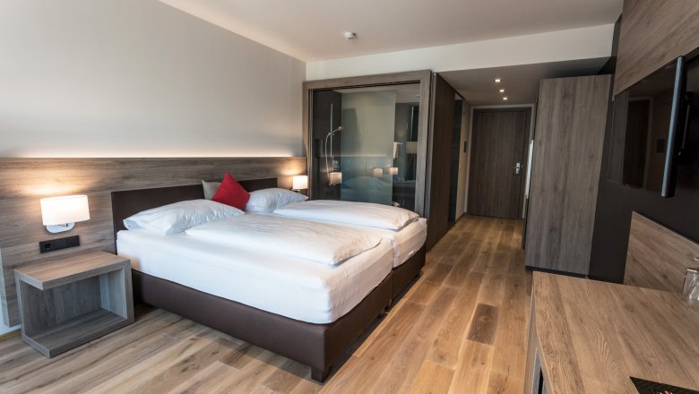 Room example wine lodge with wooden furnishings, © KASTNER NEW MEDIA - kastner.tv Modern hotel room with double bed, wooden floor and glass shower.