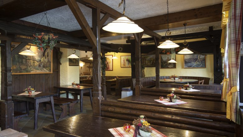Old wine tavern at the Rehrl-Fischer, © Monika Loeff Interior view of a traditional wine tavern with wooden tables and benches, decorated with tablecloths and flower arrangements.