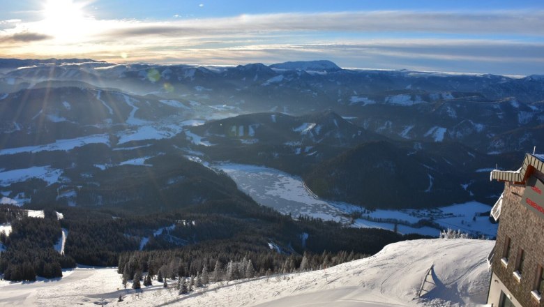 Fantastic views, © Gemeindalpe Mitterbach Winter landscape with snow-covered mountains and the frozen Erlaufsee lake at sunset.