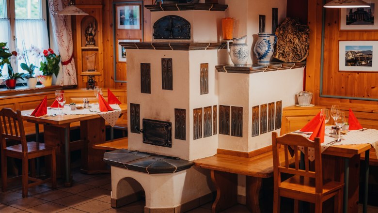 Cozy living room, © Niederösterreich Werbung/Daniela Führer Cozy parlor with tiled stove, wooden furniture and laid tables.