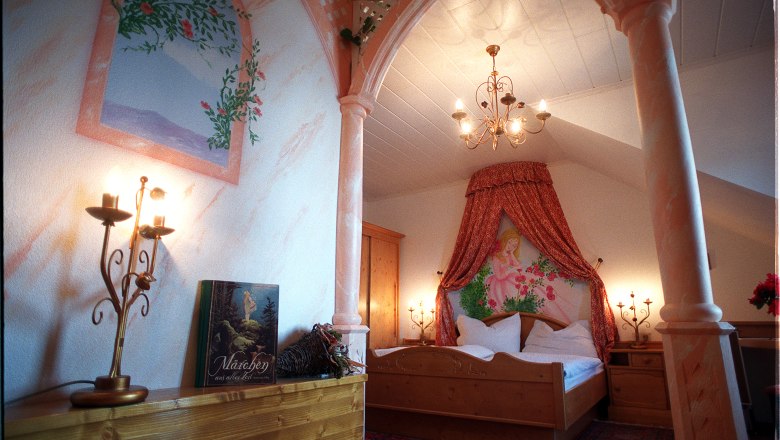 Sleeping Beauty room, © Andreas Schmidt A romantically decorated bedroom with a canopy, candlesticks and a fairytale book on a shelf.