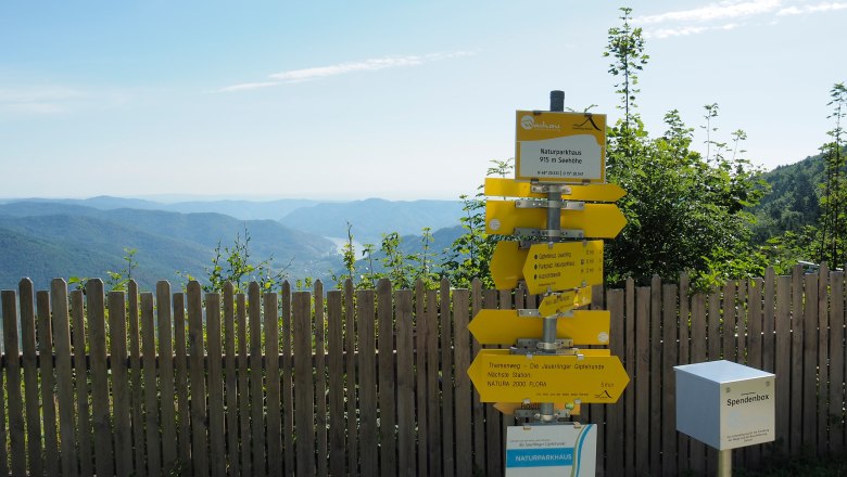 Signposting on the Jauerling, © Donau NÖ/JMZ Signpost on the Jauerling with a view of wooded hills and blue sky.
