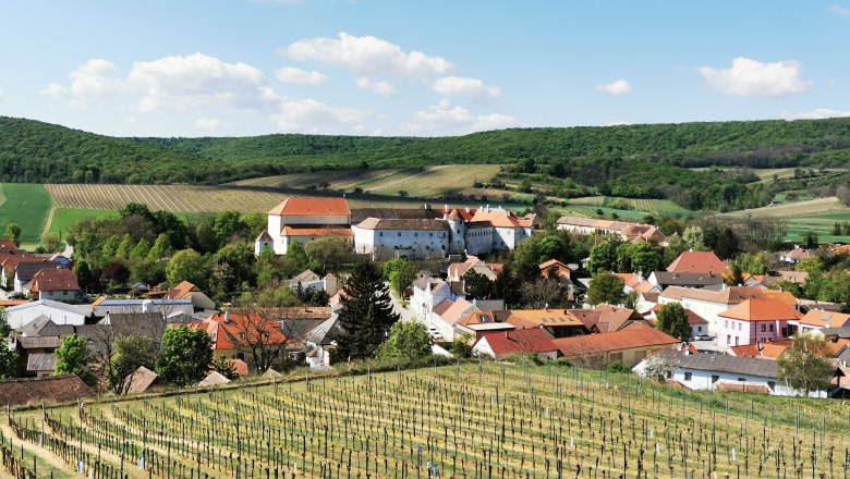 Enjoy and pause for thought in the Hundschupfen vineyard, © Weinstraße Weinviertel View of a village with vineyards in the foreground and hills in the background.