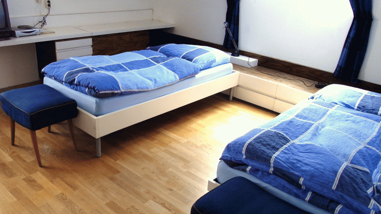 Linke Gert, Mag., © Mag. Linke A bright bedroom with two single beds, blue comforters and a skylight.
