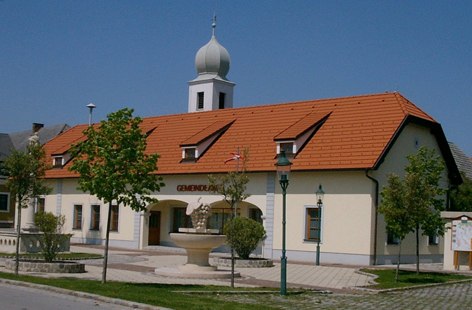 Göttlesbrunn-Arbesthal, © Gemeinde Göttlesbrunn-Arbesthal Municipal office in Göttlesbrunn-Arbesthal with red roof and tower.