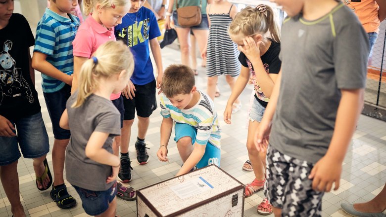 During the treasure hunt, © Michael Schafranek Children stand around a treasure chest lying on the floor.