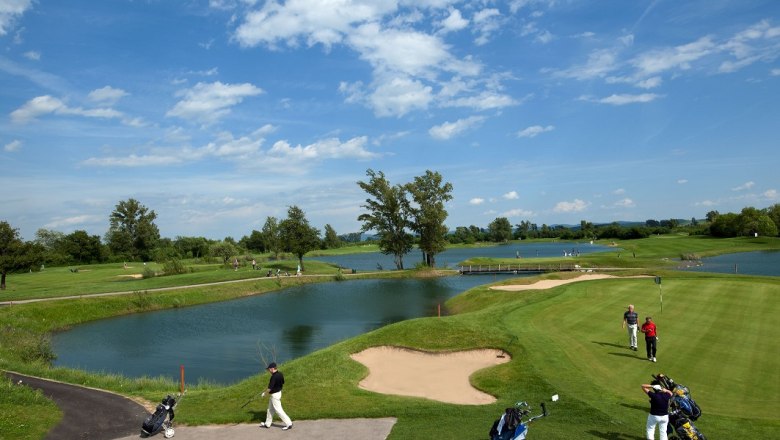 Diamond Country Club, © DCC Golf course with water hazards and players under a blue sky.