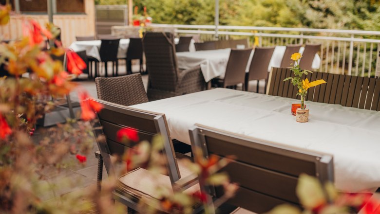 The space in the guest garden, © Niederösterreich Werbung/Daniela Führer An empty guest garden with laid tables and flowers in vases.