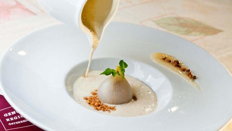 Delicacies from the kitchen, © Molzbachhof Gourmet dish with onion and foam sauce on a white plate.
