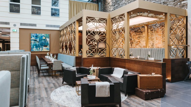 Café Wohnzimmer in the EKZ Steiner Tor, © FMS Steinertor Gastronomie BetriebsgmbH Interior view of a stylish café with modern furniture and decorative walls.