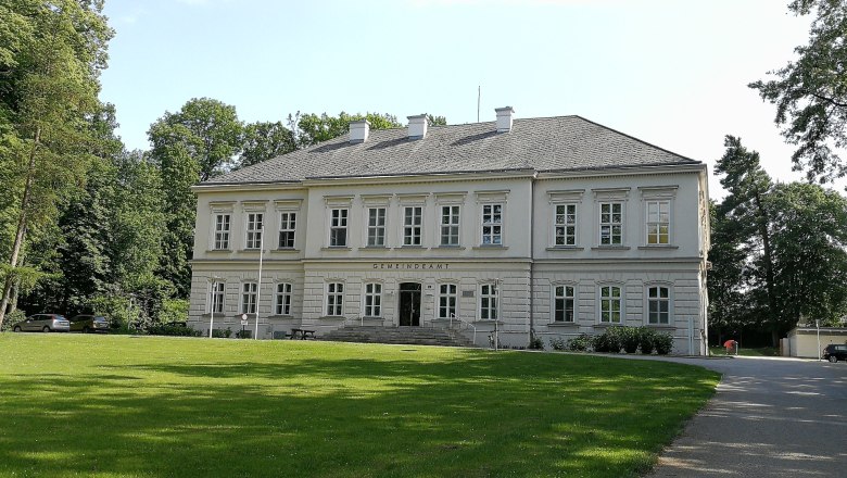 Würmla Castle, © Roman Zöchlinger Würmla Castle, a two-storey building with a gray roof and white walls, surrounded by trees and lawns.