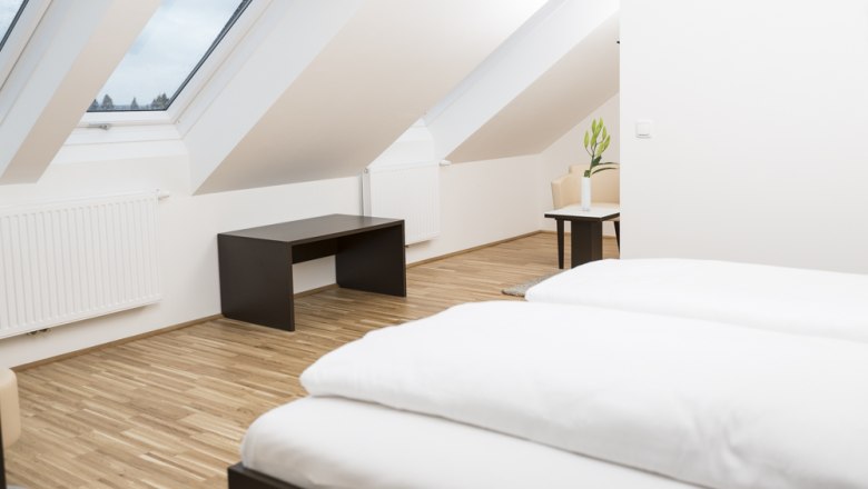 Guest room, © Ernst Jöchlinger Modern guest room with skylights, wooden floor and minimalist furnishings.