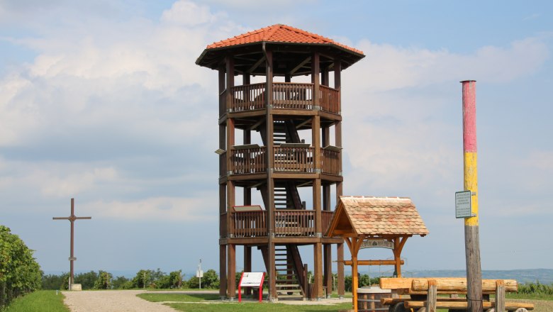 Observation tower in Roseldorf, © Gemeinde Sitzendorf Wooden lookout tower with red roof on a meadow, next to it a wooden cross and a bench.