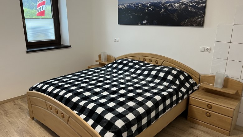 Bedroom with double bed, © Anton Sommer Bedroom with double bed, checkered comforter cover and mountain picture on the wall.