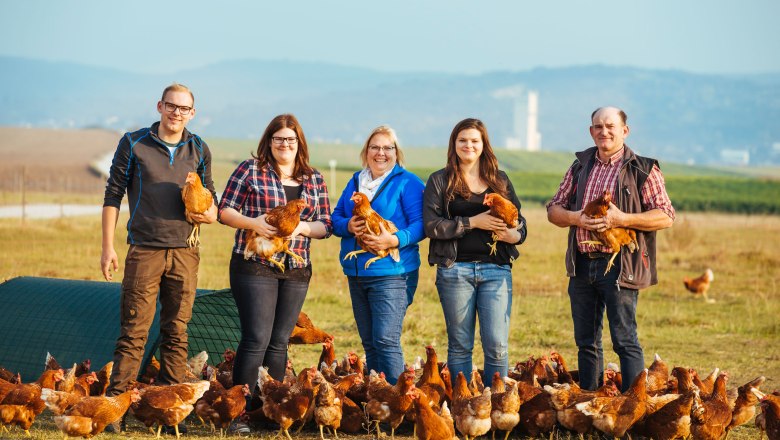 Biohof Unger, Unger family, © Maria Noisternig A family stands in a field with chickens and holds some in their arms.