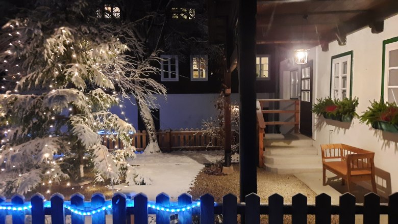 Country estate Oberhof, © Landsitz Oberhof Snow-covered garden with illuminated tree and house veranda at night.