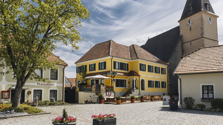 Refreshments in Maria Laach, © Niederösterreich Werbung/David Schreiber Idyllic village square with inn and terrace and a church tower in the background.