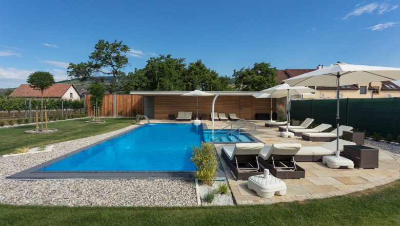 Outdoor pool with sun loungers, © KASTNER NEW MEDIA - kastner.tv Modern outdoor pool with sun loungers and parasols in a well-tended garden.