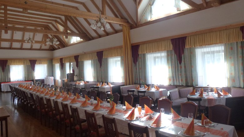 Griessler Inn, © zur Verfügung gestellt: Gasthaus Griessler Interior view of an inn with covered tables and wooden beamed ceiling.