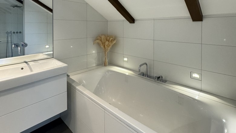 Bathroom, © Juwel am Stadtrand Modern bathroom with bathtub, washbasin and sloping ceiling with wooden beams.