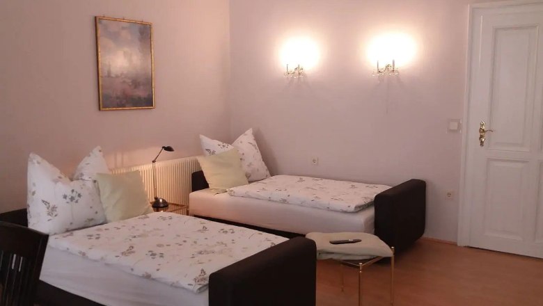 Single beds in the old town apartment Mathilde, © Fam. Obernberger Two single beds in a bright room with wall lamps and a painting on the wall.