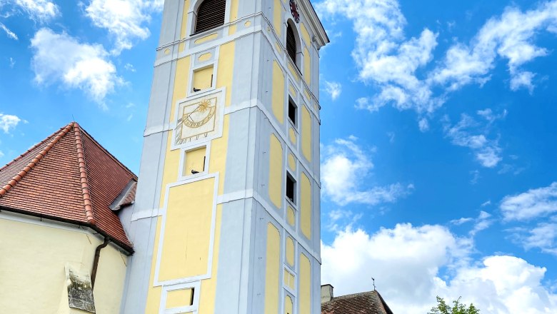Leaning tower of Waitzendorf, © Weinstraße Weinviertel Leaning tower in Waitzendorf with yellow facade and clock, surrounded by blue sky and clouds.