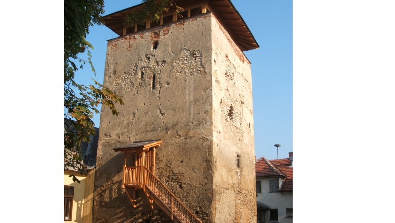 Palterndorf defense tower, © Herbert Nowohradsky An old fortified tower with a crumbling façade and a wooden staircase, surrounded by houses and trees.