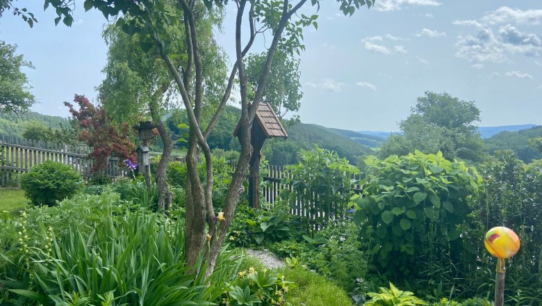 Apartments Riedl, © Wiener Alpen A green garden with trees, shrubs and a wooden fence in the background.