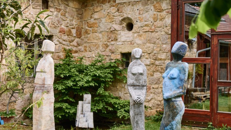 Good gas part, © Nina Nagy Photography Three colorful sculptures stand on a meadow in front of an old stone building