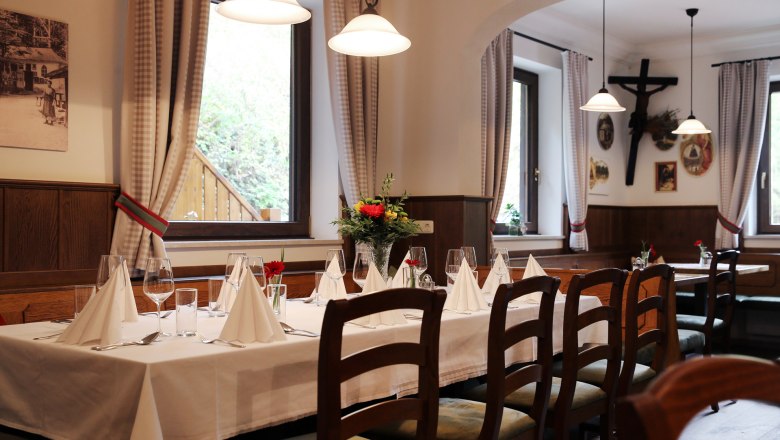 Interior of the Waldgasthof Steinbründl, © Familie Kogler-Renner Interior of a cozy inn with a set table, wooden furniture and decorations on the walls.