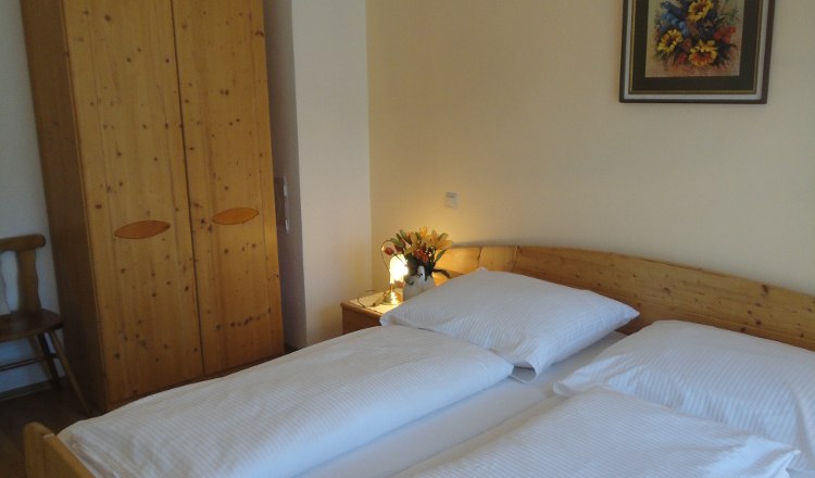 House King, © Fam. König A cozy bedroom with double bed, wooden wardrobe, bedside table with flowers and a painting on the wall.