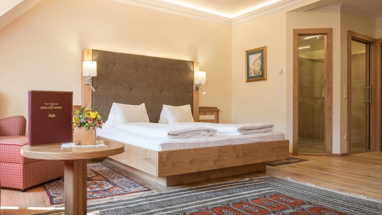 Rooms at the Hotel Kirchenwirt, © Kirchenwirt Hotel room with double bed, carpets and wooden furniture.