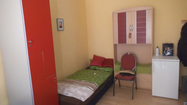 Single room, © Privatzimmer Jana Emmerova A small single room with a bed, red wardrobe, chair and small fridge.