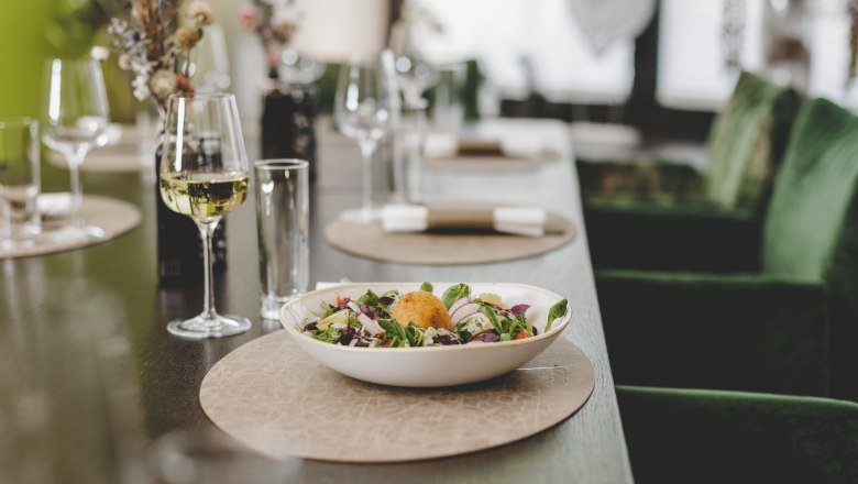 Varied menu with local products, © Niederösterreich-Werbung/David Schreiber A laid table with a plate of salad and a glass of white wine.