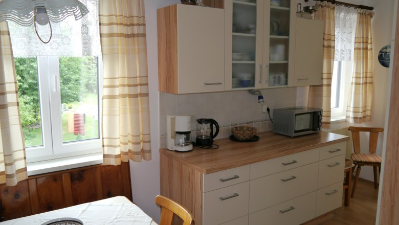 Kitchen, © fbeck Cozy kitchen with wooden furniture, table, chairs, coffee machine and microwave. Window with curtains, view of the garden.
