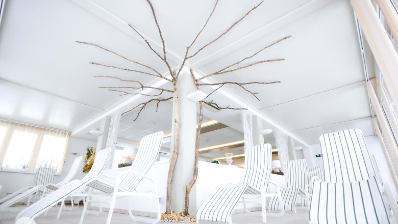 Rest area, © TheVerve-Agentur (theverve.at) A bright relaxation area with white loungers and a decorative tree trunk in the middle.