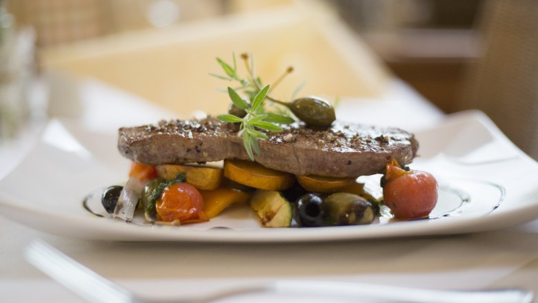 Alpen-Aktiv-Landgasthof zur Schubertlinde, © Patrick Haberler A plate with a piece of meat, garnished with vegetables and herbs.