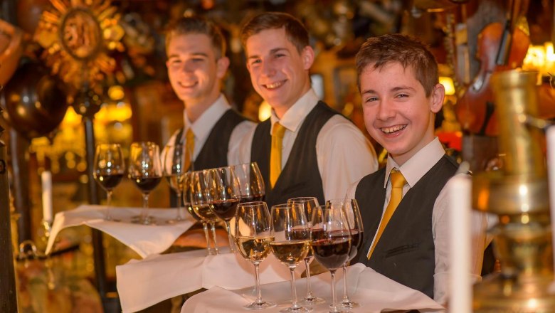 Marchfelderhof, © Gault Millau Three waiters in a restaurant with trays full of wine glasses.