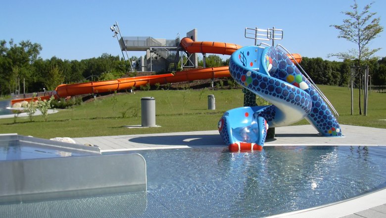 Aquapark, © Stadtgemeinde Herzogenburg View of an aqua park with a blue children's slide and a large orange water slide in the background.