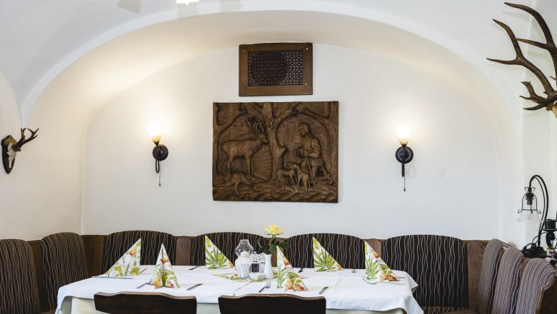 Game in the kitchen and dining room, © Niederösterreich Werbung/David Schreiber Cozy guest room with wood paneling and hunting motifs on the wall.