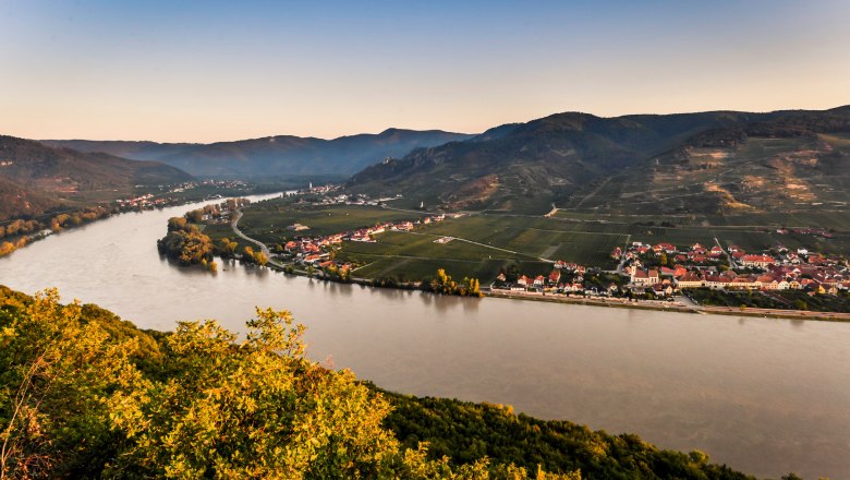 View from the Ferdinand-Warte, © Robert Herbst Panoramic view of a river, surrounded by hills and villages, at sunset.