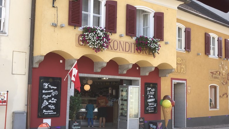 Cafe Intakt in the center of Pöchlarn Exterior view, © Donau NÖ Tourismus GmbH Exterior view of a café with a yellow façade, red shutters and floral decorations.