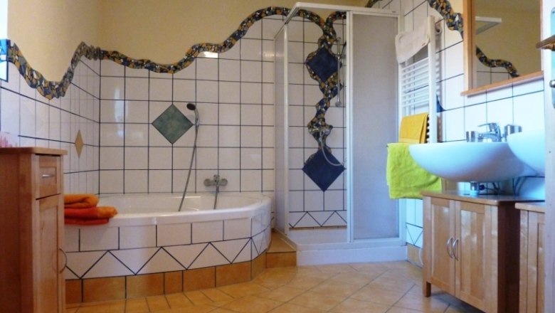 Bathroom, © Daniel Fries A bathroom with corner bath, shower, washbasin and tiles in blue and white.